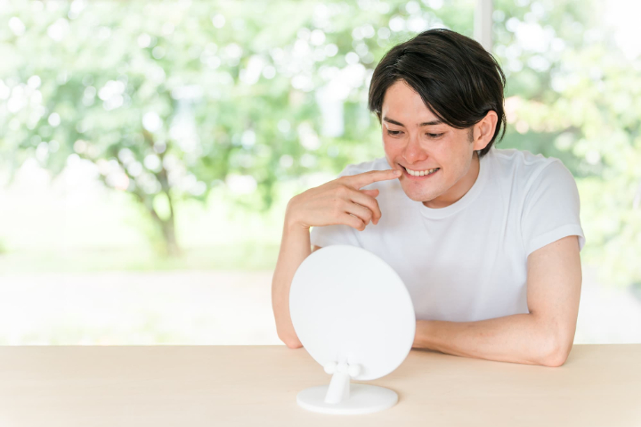 出っ歯かもと気にして前歯を鏡で見る男性