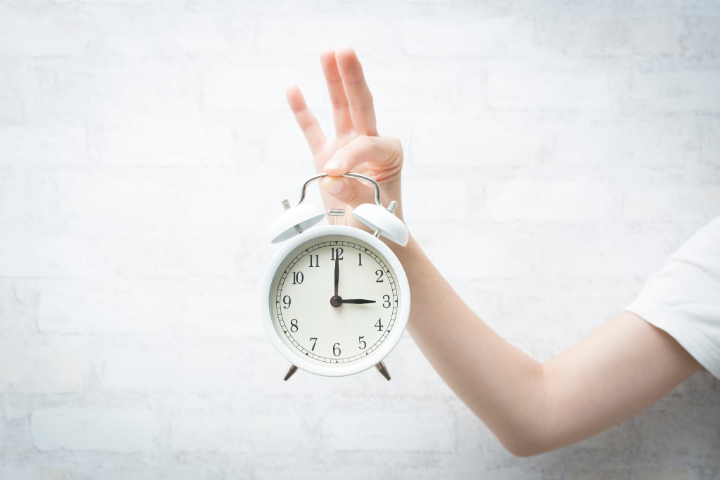 置時計を持つ女性の手元