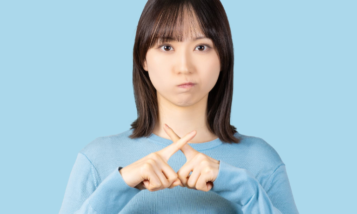 指でバツを作る女性
