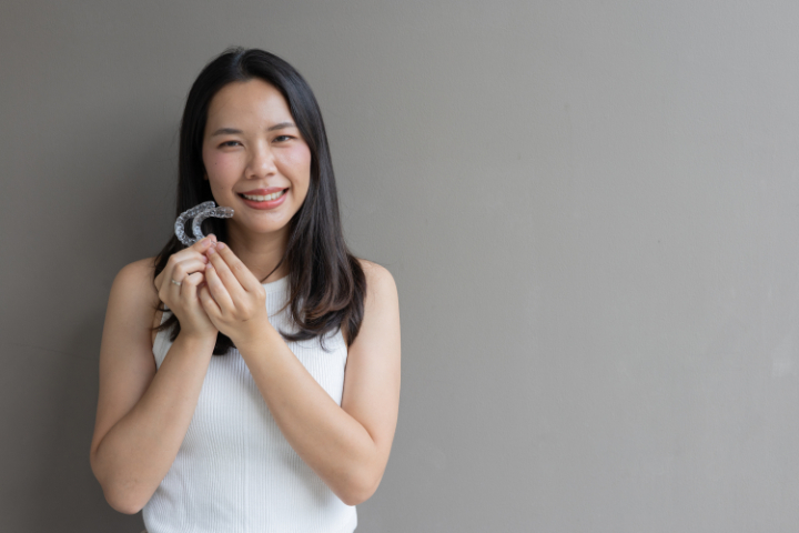インビザラインを手に笑顔を見せる女性