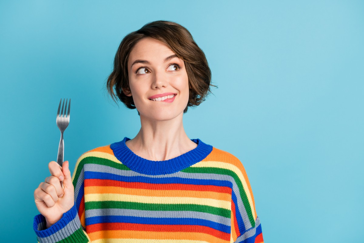 根管治療後はいつから食事できるのかフォークを手に考えている女性
